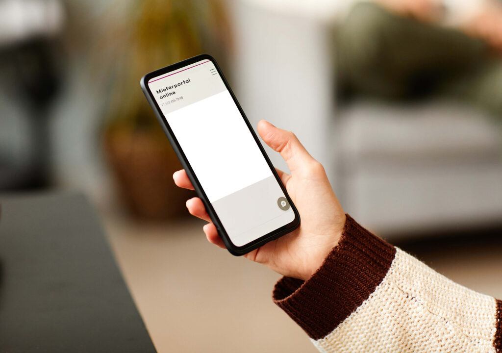 Hand hält ein Smartphone mit der App Mieterportal Online der Wohnbau Lörrach